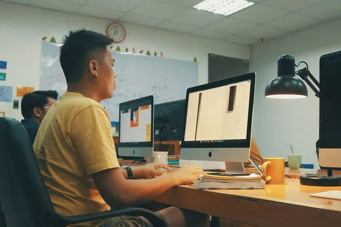 Office workers at computers, illustrating unhinged ways to deal with coworkers, in a shared workspace.