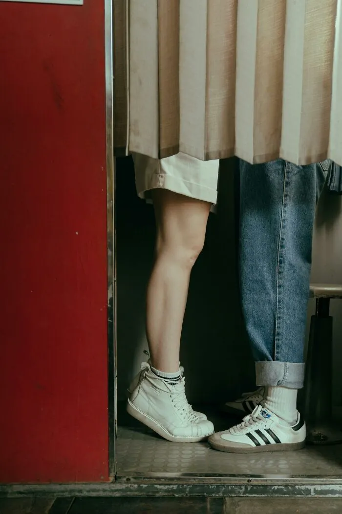 Two people standing close in a tight space, one wearing white sneakers, capturing an unusual real-life glitch moment.