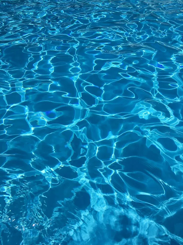 Wavy reflections creating an illusion in a blue swimming pool, resembling a glitch in the matrix.
