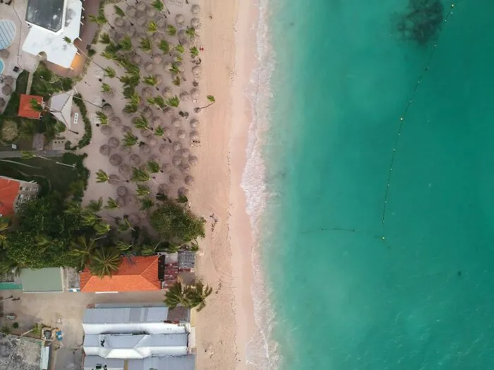 Aerial view of a tropical beach, ocean meeting sand, capturing a real-life glitch in the matrix vibe.