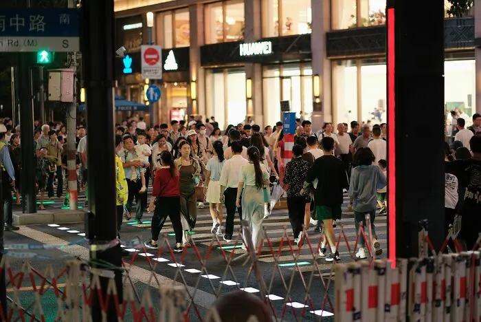 People crossing a busy street with reflections creating a glitch-like effect, highlighting a real-life Matrix moment.