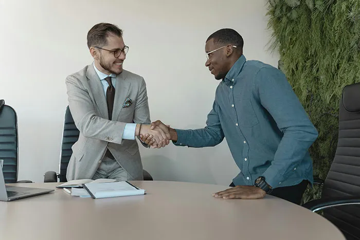 Two young people shaking hands in a professional setting, possibly discussing insights shared by boomers.