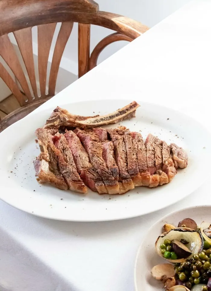 Sliced grilled steak on a plate with a side of mixed vegetables representing restaurant food items.