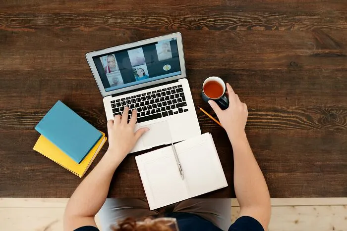 Person on a virtual job interview, using a laptop and holding a cup, highlighting a potential red flag in a job interview.