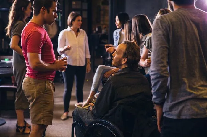 Group of people socializing indoors at a restaurant with restaurant food and drinks during a casual gathering.