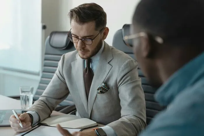 Two professionals in a job interview setting, one taking notes, discussing biggest red flag indicators.