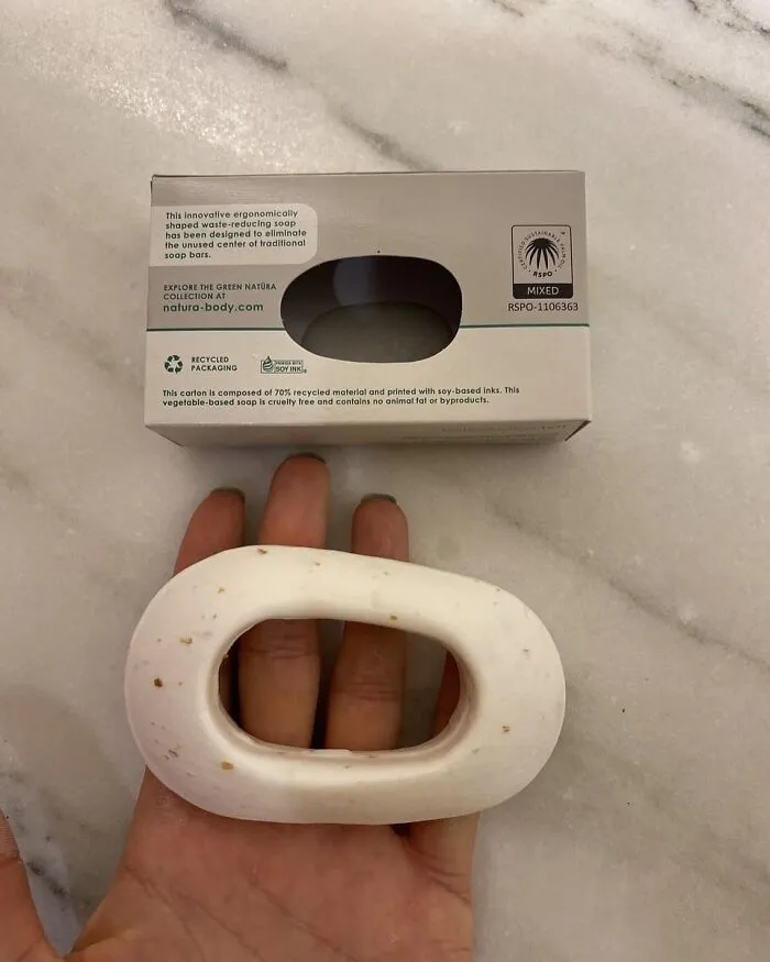 Hand holding a uniquely shaped soap bar with eco-friendly packaging, highlighting cool design concepts.