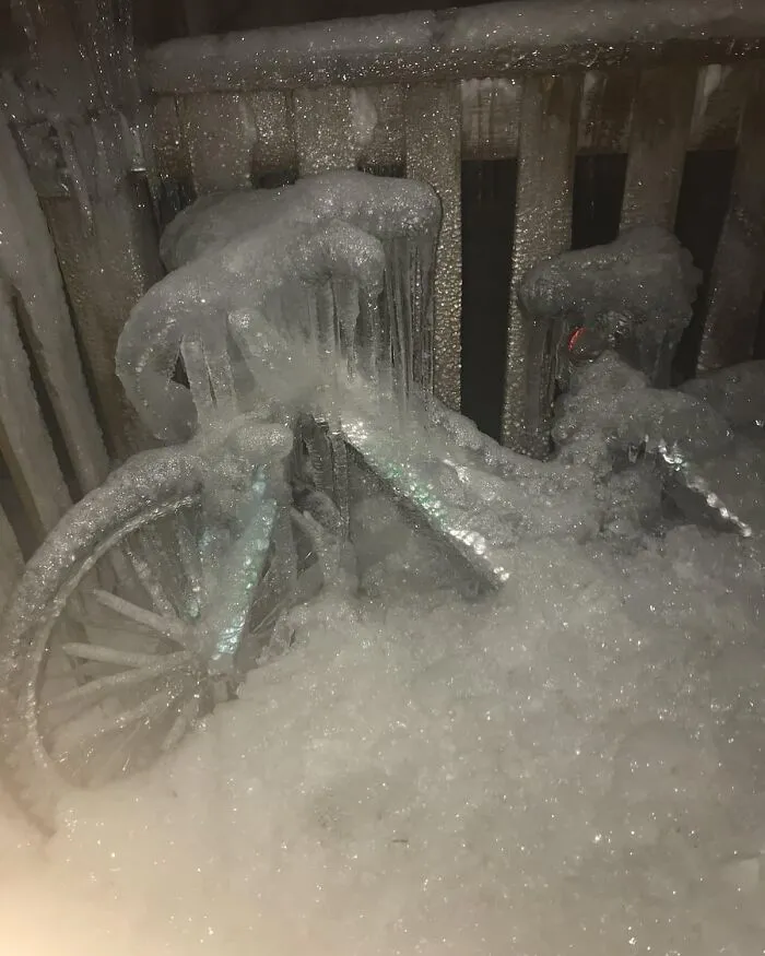 Frozen bicycle covered in ice near a wooden railing, showcasing a cool and random winter scene.