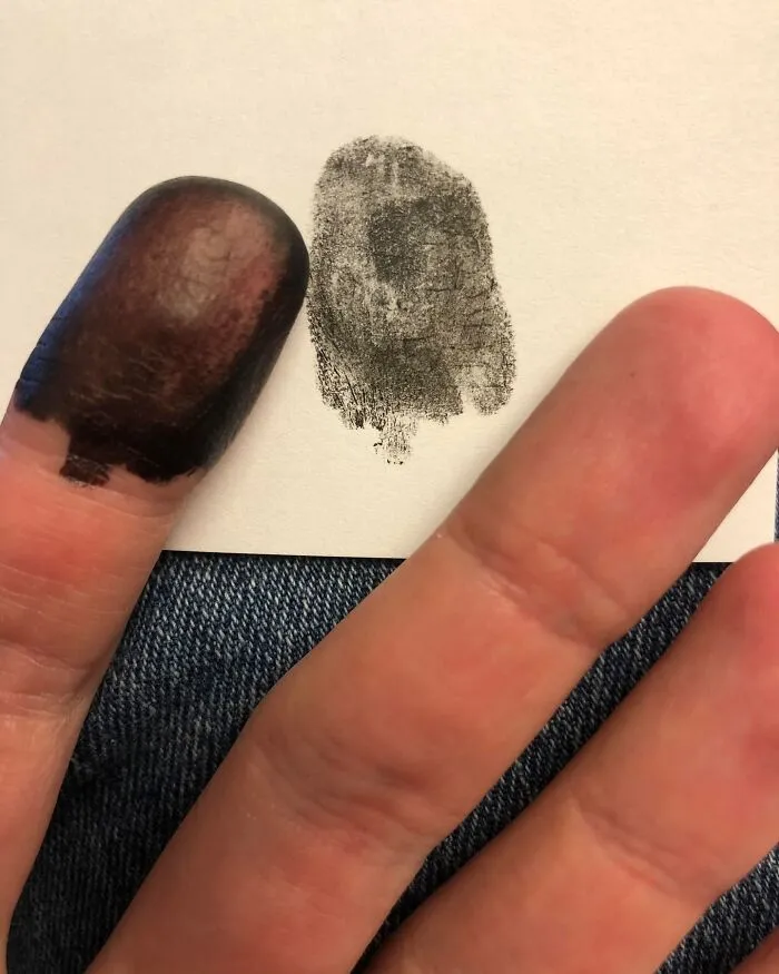 Black inked thumb next to its fingerprint on paper, a cool and random image.