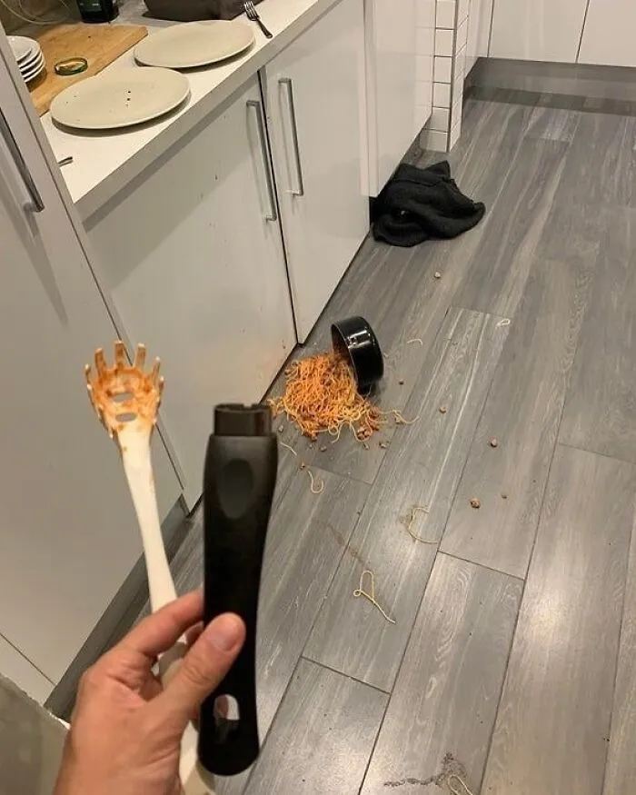 Broken kitchen utensil with spilled spaghetti on the floor, creating a random and cool mess.
