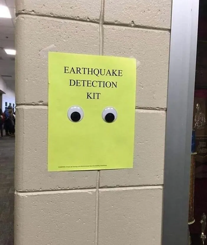 Googly eyes on a sign titled "Earthquake Detection Kit" on a wall, adding humor and a sprinkle of joy.