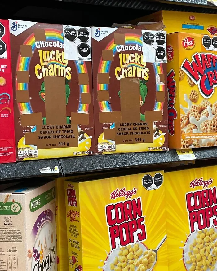 Boxes of various cereal brands, including Chocolate Lucky Charms and Corn Pops, displayed on a supermarket shelf.