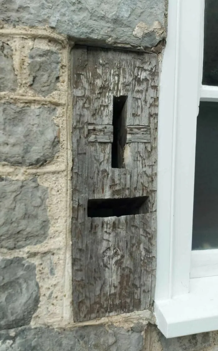 ¿Qué son estas ranuras en el costado de una antigua casa de piedra al lado de una ventana?