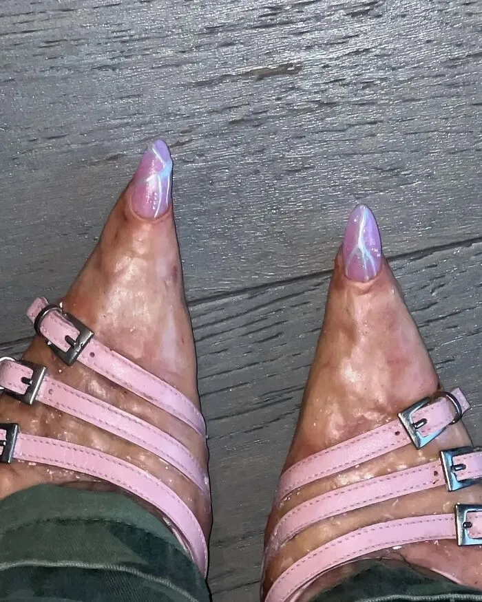 Close-up of feet with glossy, oddly shaped toes wearing pink strappy heels, creating an uncomfortable visual impression.