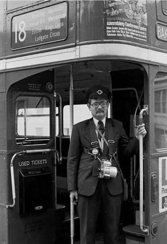 Vintage bus conductor standing at the entrance of a double-decker bus, showcasing antique historical photographs style.