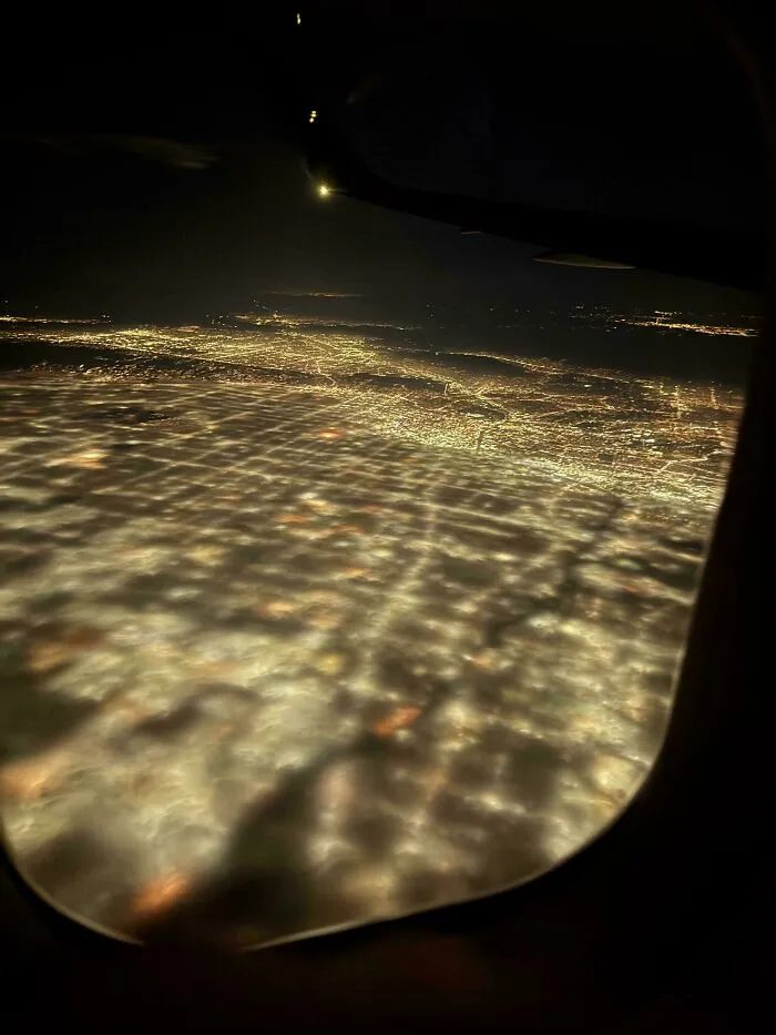 Vista nocturna curiosa desde avión mostrando luces de ciudad y nubes, fotos curiosas que permiten ver otra perspectiva.