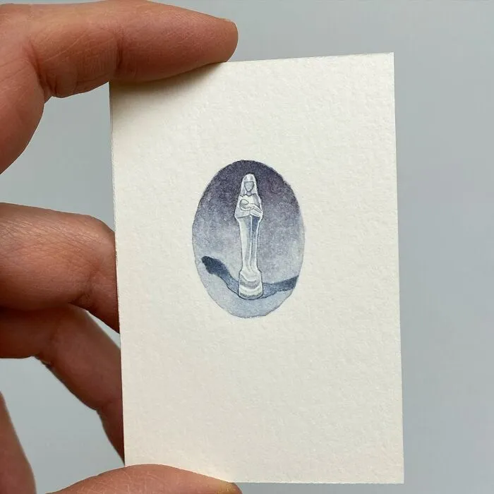 Hand holding a tiny one-inch painting of a chess piece resembling a queen in muted tones by Brooke Rothshank.