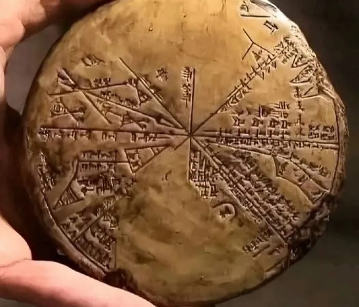 Ancient clay artifact with detailed inscriptions and markings held in hand, showcasing archaeology and architecture history.