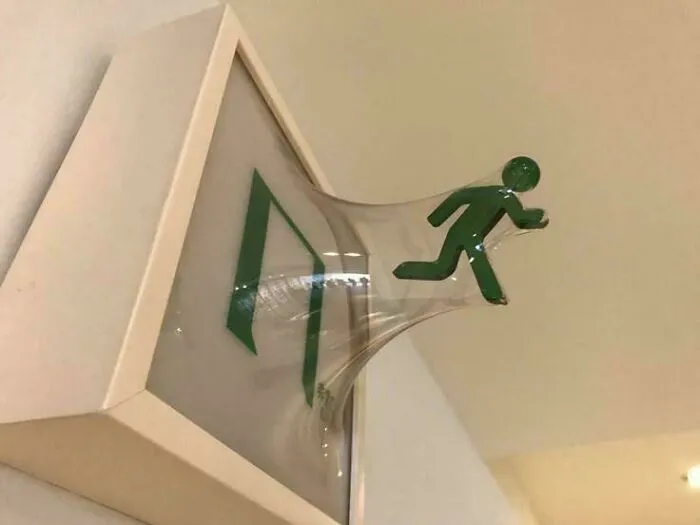 Figura verde saliendo de una señal de salida en una imagen creativa que parece bendecida y maldita al mismo tiempo