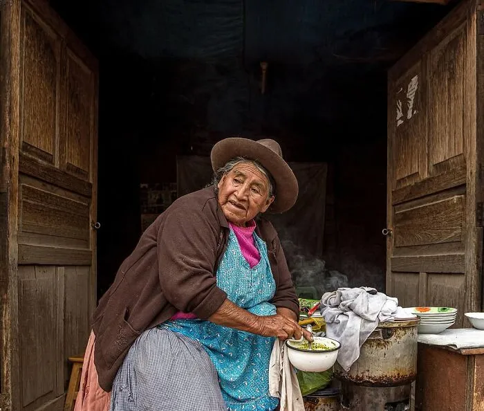 Retrato elocuente de persona mayor en cocina tradicional, mostrando cultura y vida cotidiana en el mundo.