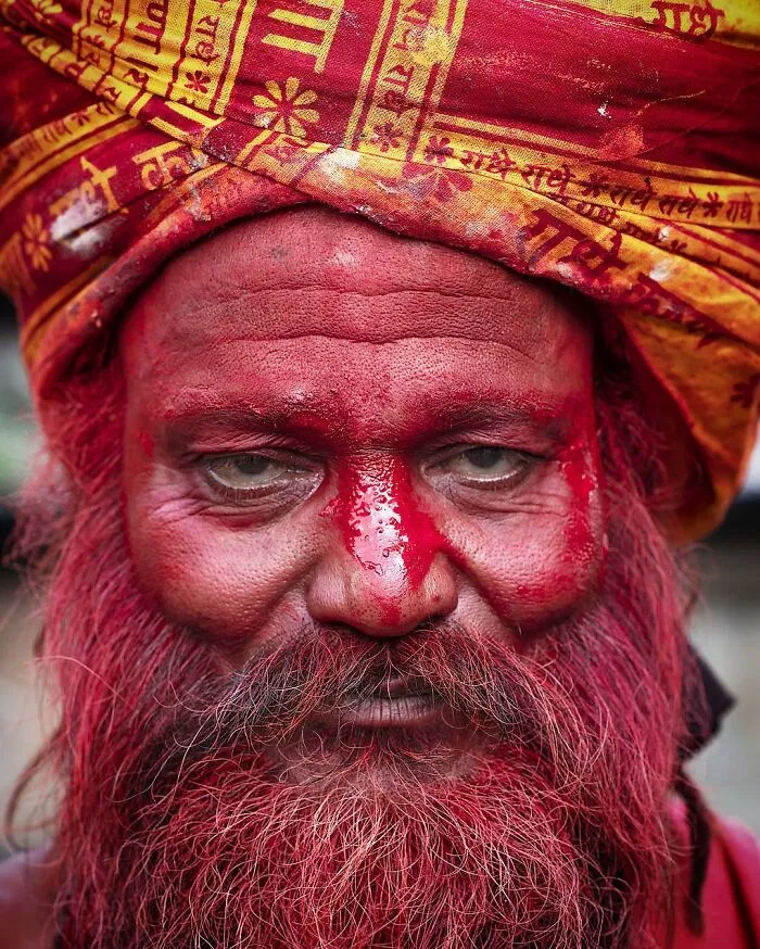 Retrato elocuente de persona mayor con turbante amarillo y rostro pintado de rojo, parte de serie mundial de Massimo Bietti.