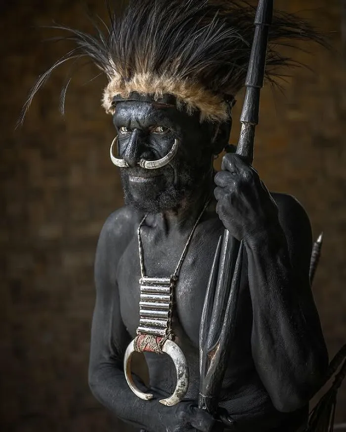 Retrato elocuente de persona mayor con pintura corporal negra y adornos tradicionales en el mundo, fotografía de Massimo Bietti.