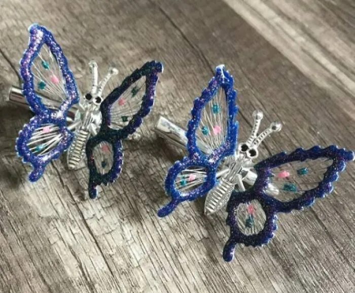 Butterfly hair clips with colorful beaded edges on a wooden surface representing cringey nineties fashions.
