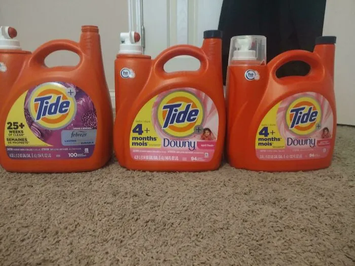 Three Tide laundry detergent containers showing products getting smaller and more expensive over time comparison on carpet floor.