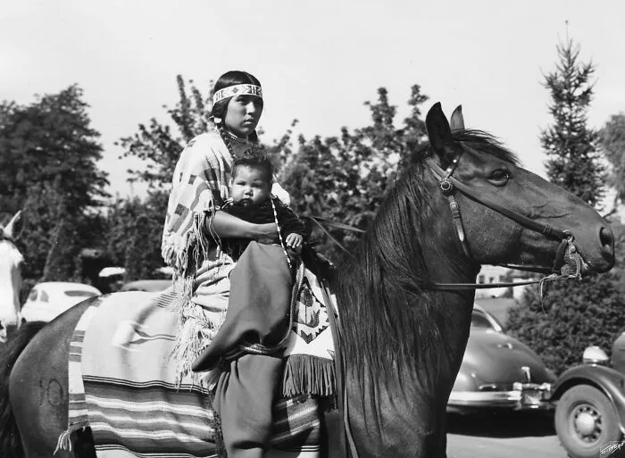 An Indian Woman And Child Ride On Horseback In A Parade During The Pendleton Round-Up