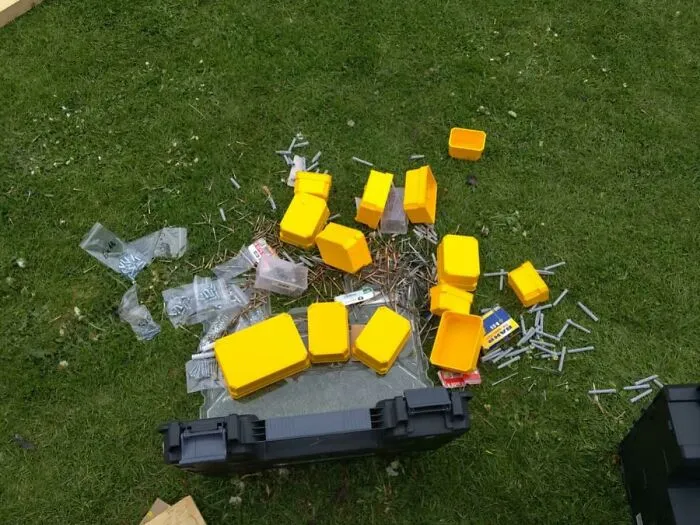 Unexpected fails with scattered yellow containers and hardware pieces spilled on the grass in an unfortunate outdoor setting.
