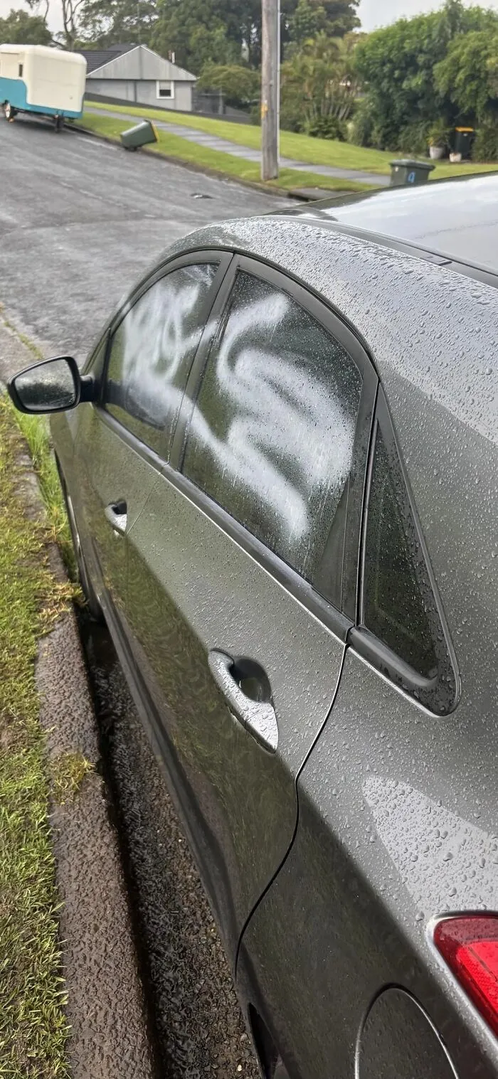 Car window covered in spray paint on a rainy day, an unexpected fail fitting the anything gone wrong category.