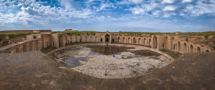 Panoramic view of a stunning UNESCO treasure with ancient arches and a partially flooded courtyard under a blue sky.