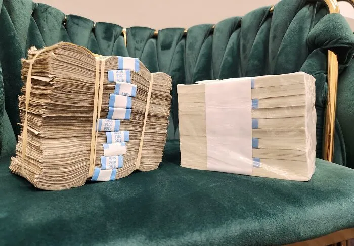 Stacks of worn and crisp folded bills displayed on a green velvet chair showing money before and after changes