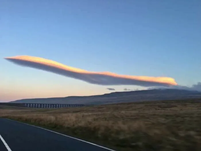 Nube curiosa y alargada en el cielo que parece un objeto interesante en un paisaje abierto al atardecer.