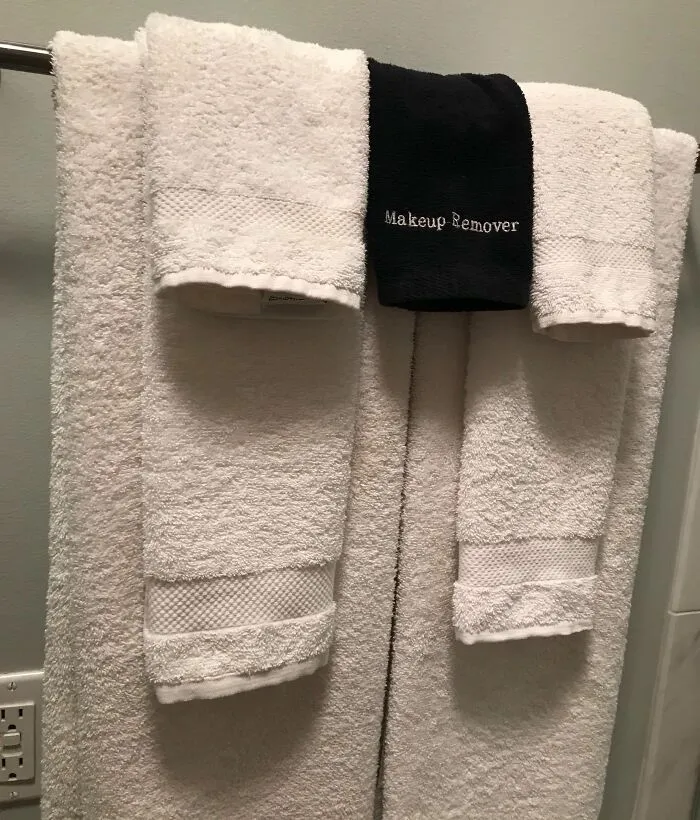 Juego de toallas blancas y negra para desmaquillar, organizadas en barra de baño, solución genial para orden y limpieza.