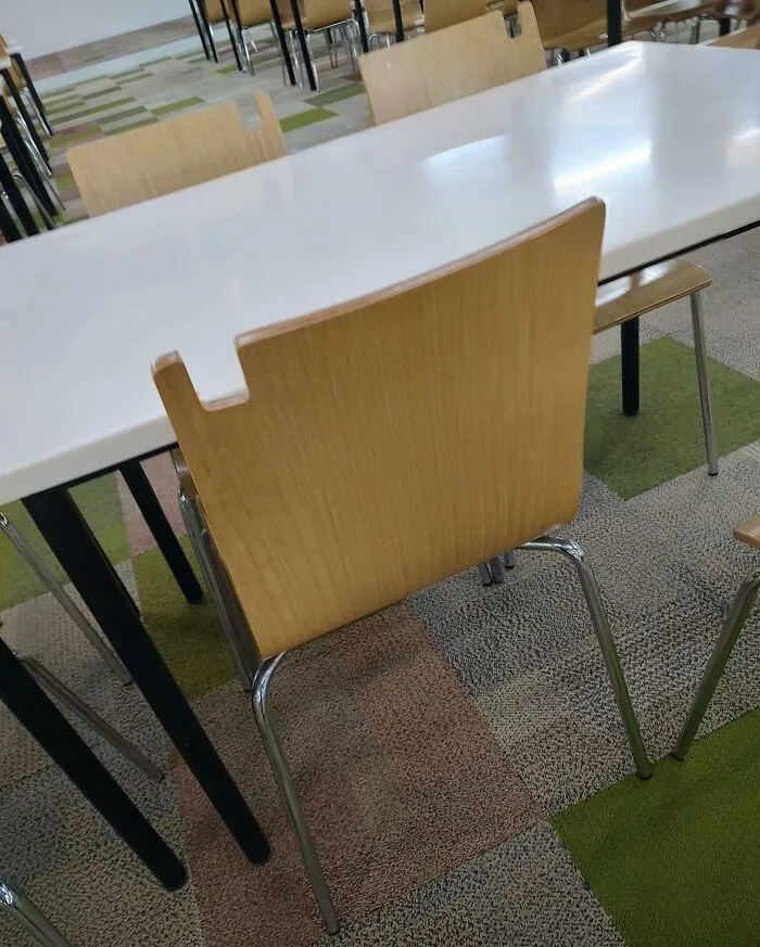 Esta silla en una cafetería de oficina tiene una muesca para colgar bolsas.