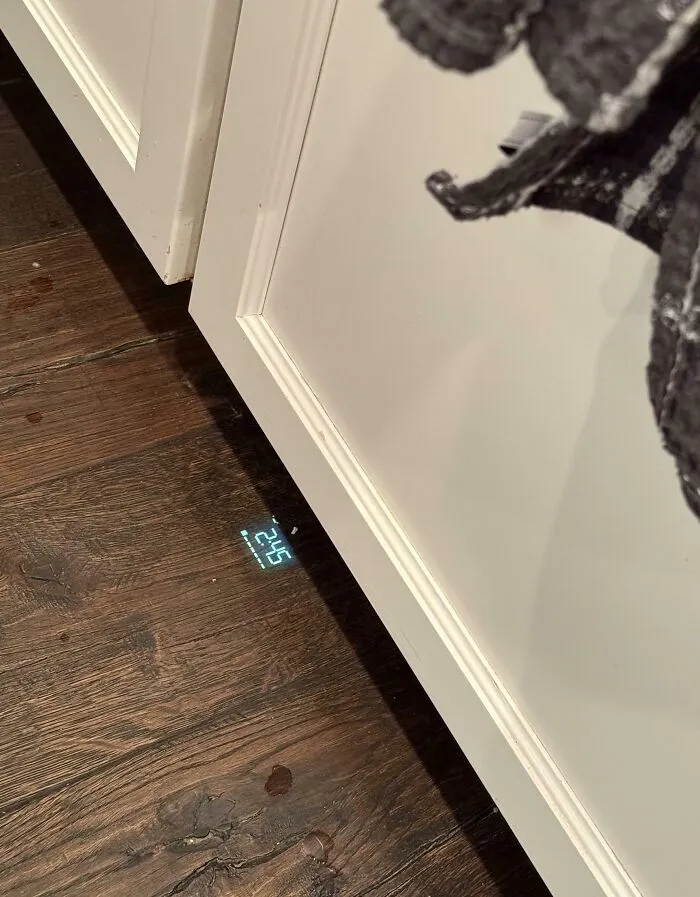 Proyección digital de reloj en suelo de madera junto a mueble blanco como solución genial a problemas habituales.