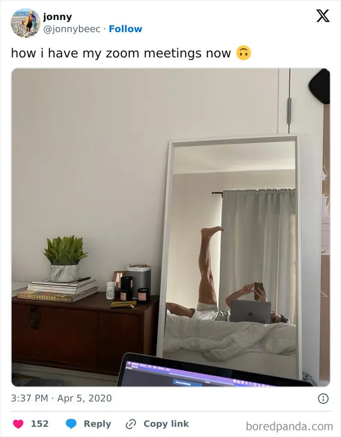Person lying in bed working on a laptop with one leg raised, humorously illustrating work-from-home life and Zoom meetings.