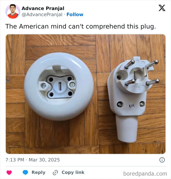 Unusual three-prong electrical plug and socket on a wooden floor, illustrating confusing American mind concept.