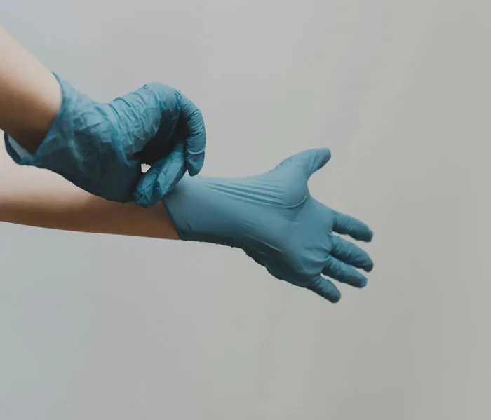 Person wearing blue medical gloves, preparing for autopsies revealing bizarre and unexpected discoveries.