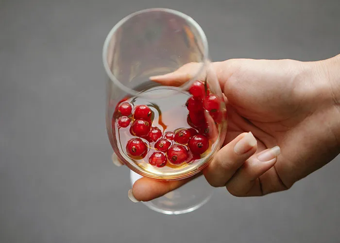 Hand holding a glass with red berries and liquid, illustrating surprisingly entertaining facts shared in a thread.