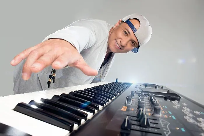 Man in a backward cap playing keyboard, representing cringey nineties fashions and nostalgic music style.