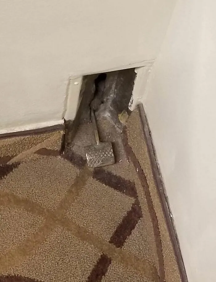 Small hidden wall opening under carpet with a strange metal hammer inside found in a home with a hidden past