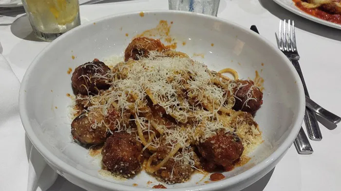 Bowl of spaghetti and meatballs topped with grated cheese, illustrating former employees revealing disturbing workplace secrets.