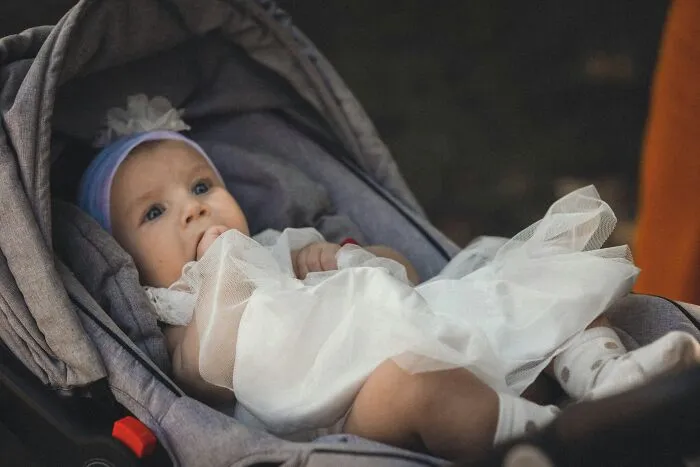 Baby girl dressed in white lying in a stroller, representing twins and unique names people have heard.