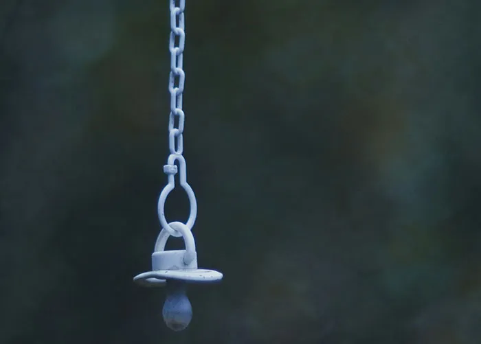White baby pacifier hanging from a chain, illustrating one of the worst gifts people have ever received.