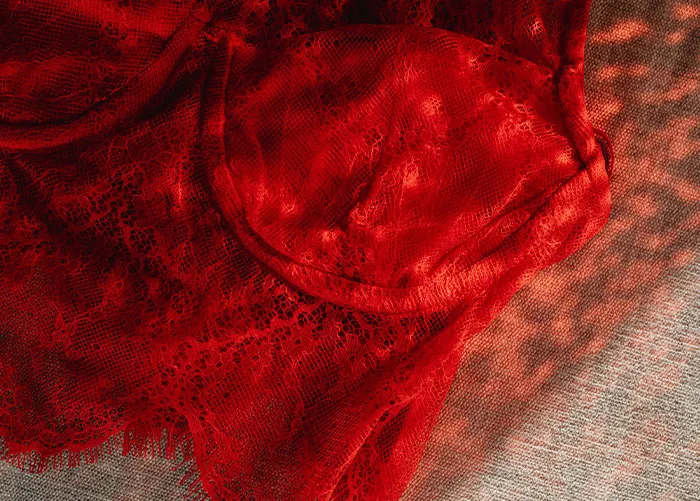 Red lace lingerie laid on a surface, illustrating one of the worst gifts people have ever received.