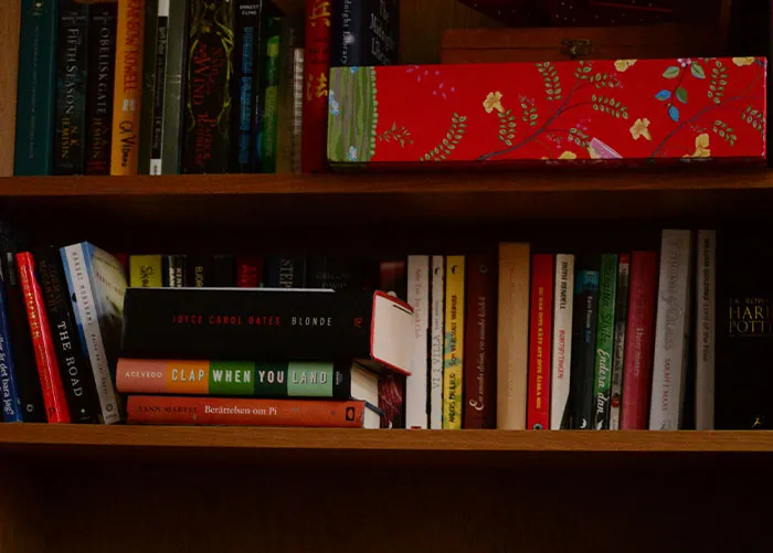 Books on a wooden shelf with a variety of colorful covers illustrating worst gifts people have ever received.