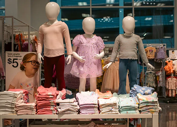 Mannequins displaying children’s clothing with folded shirts in a store, illustrating worst gifts people have received.