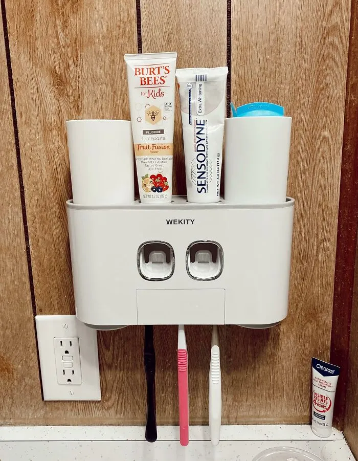 Wall-mounted toothbrush holder with toothpaste and cups, illustrating easy morning routine hacks for becoming a morning person.